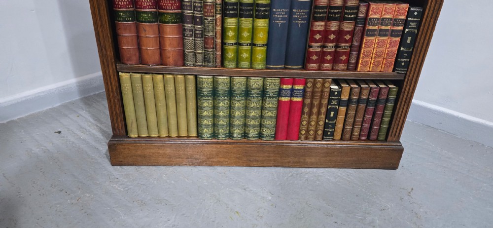 An antique oak open bookcase featuring four adjustable shelves filled with leather-bound books, twin drawers with brass handles, and fluted column side details. View IX