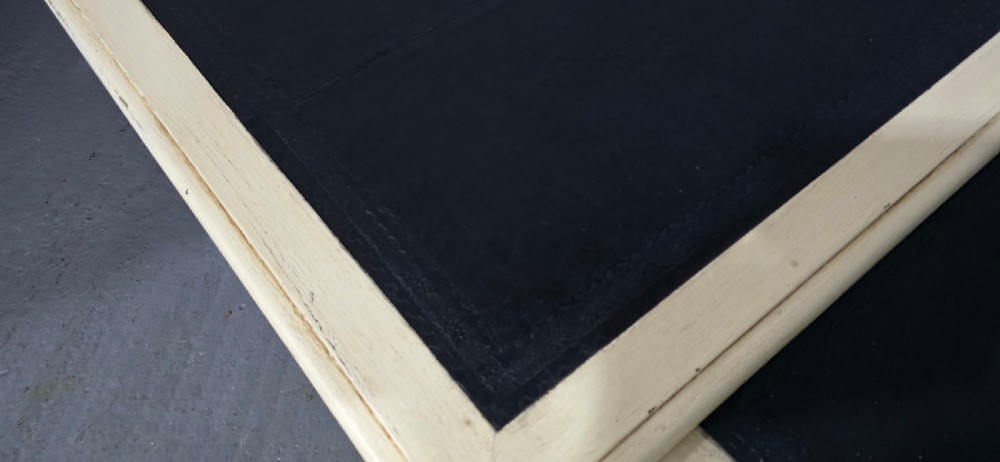 A cream painted French kneehole desk featuring a black leather inset writing surface, curved cabriole legs, and brass drawer knobs with a key and tassel hanging from the central drawer. View VII