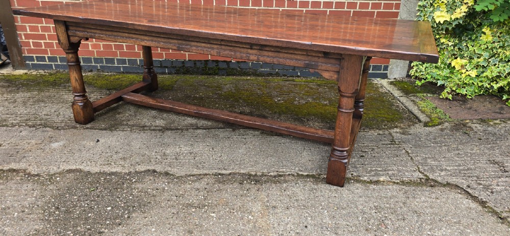 A long solid oak refectory dining table featuring a plank top, turned legs, and a low stretcher base. View VI