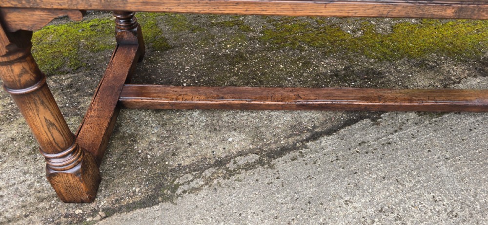 A long solid oak refectory dining table featuring a plank top, turned legs, and a low stretcher base. View VII