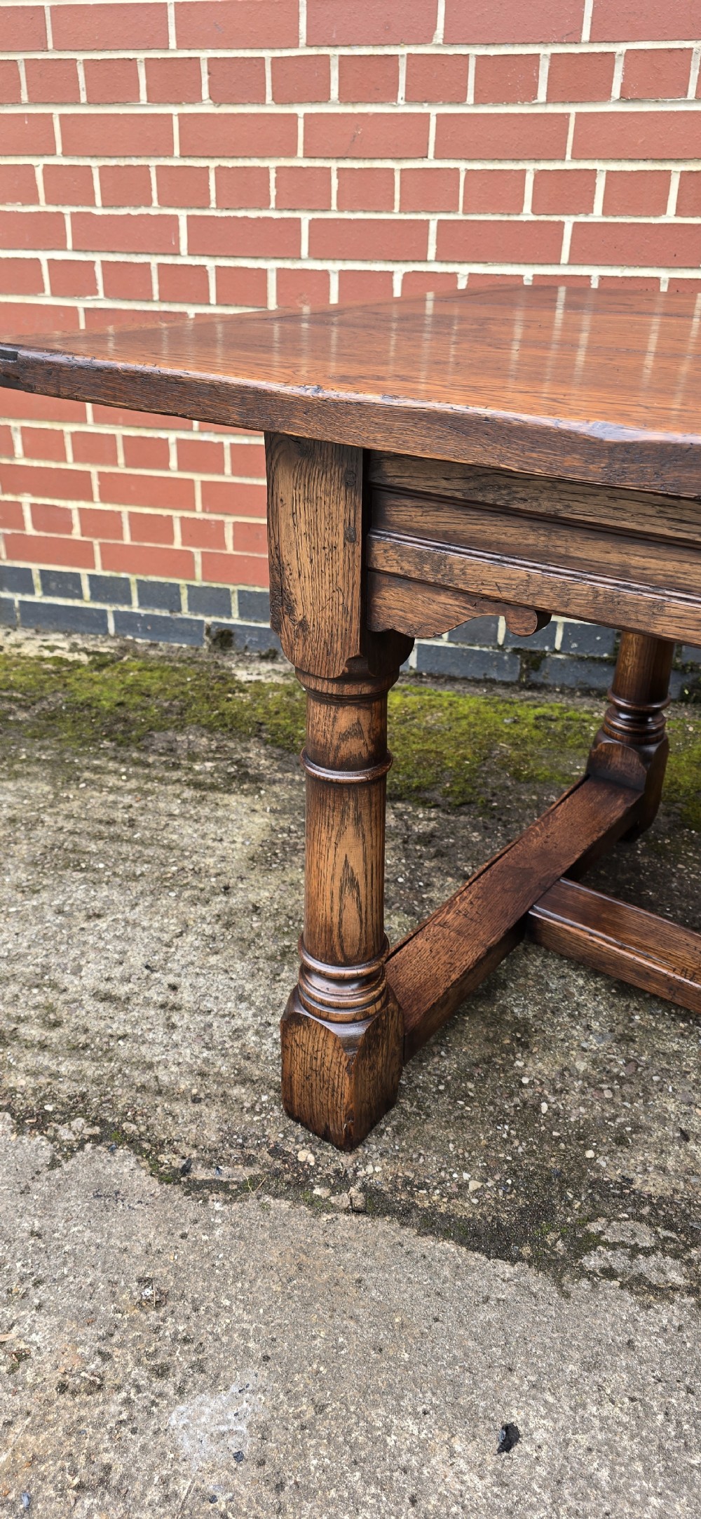 A long solid oak refectory dining table featuring a plank top, turned legs, and a low stretcher base. View VIII