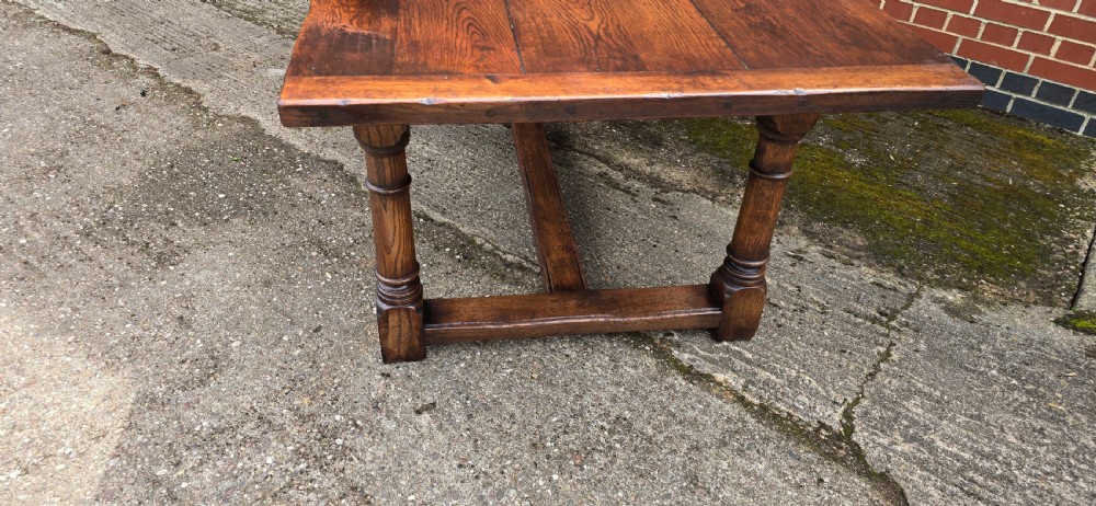 A long solid oak refectory dining table featuring a plank top, turned legs, and a low stretcher base. View XIII