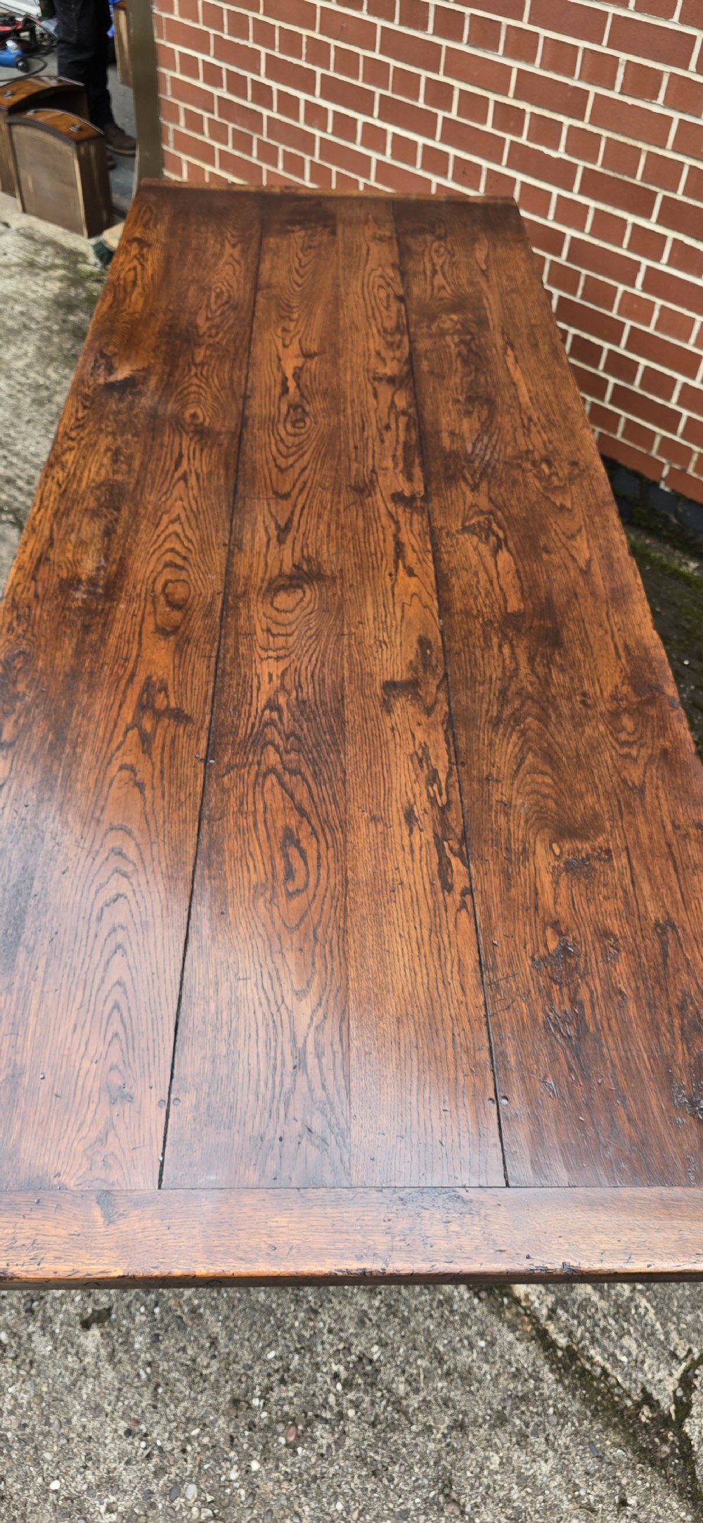 A long solid oak refectory dining table featuring a plank top, turned legs, and a low stretcher base. View XIV