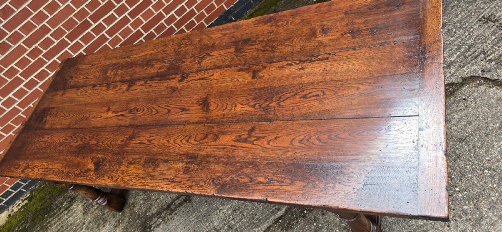 A long solid oak refectory dining table featuring a plank top, turned legs, and a low stretcher base. View XVI