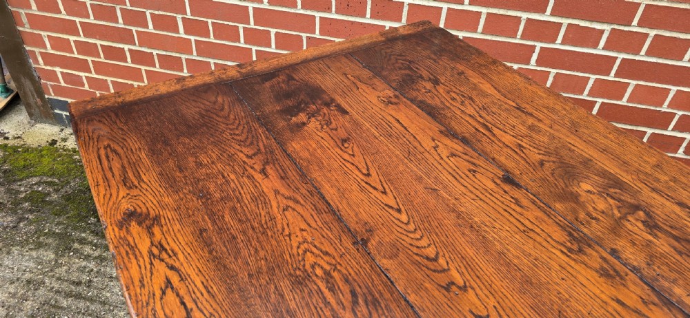 A long solid oak refectory dining table featuring a plank top, turned legs, and a low stretcher base. View XVIII