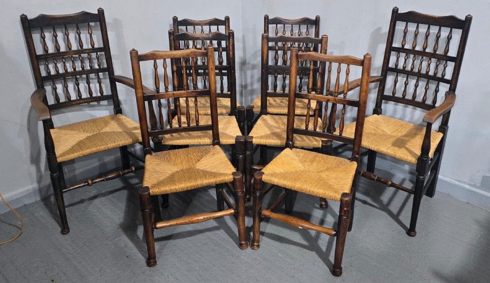 A harlequin set of eight dark oak spindle back dining chairs featuring woven rush seats, turned legs, and stretchers. View III