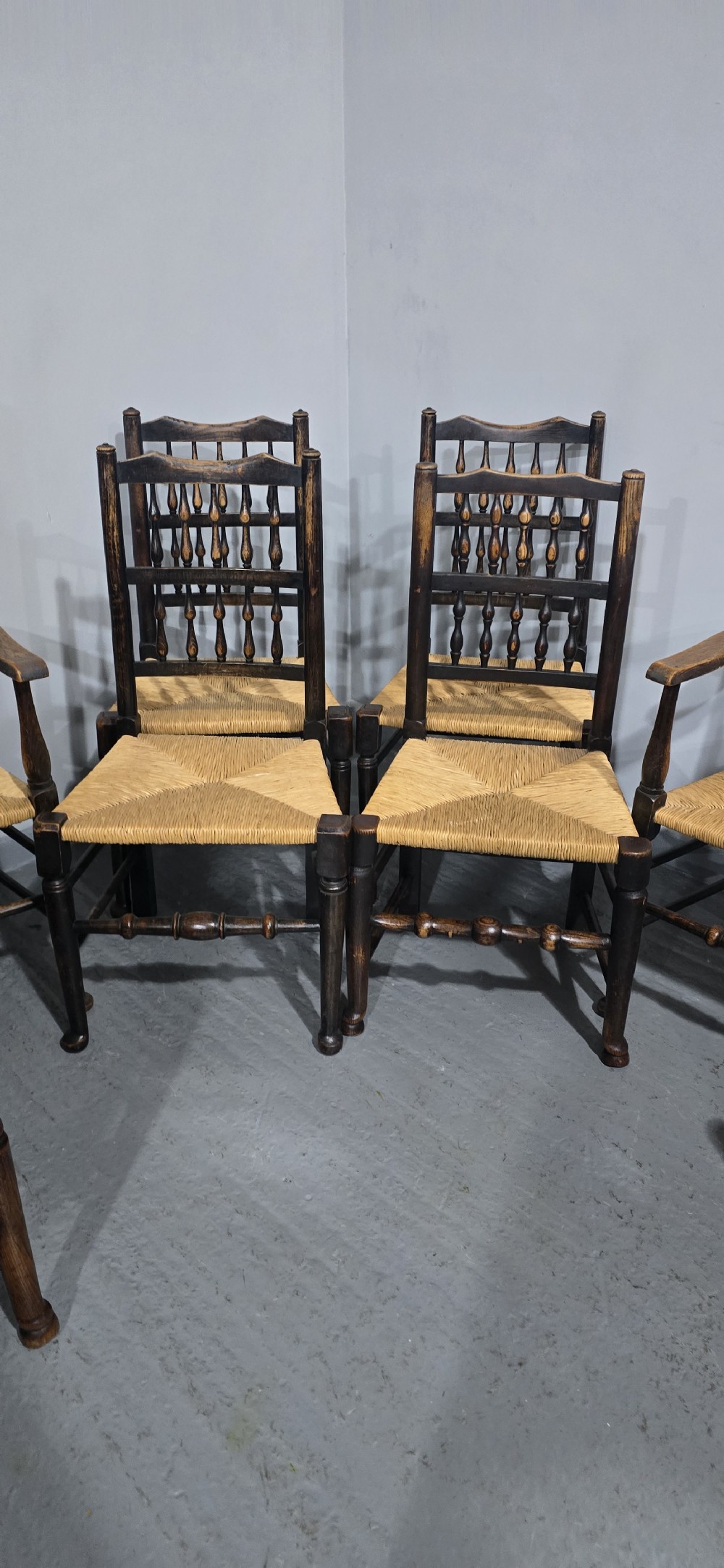 A harlequin set of eight dark oak spindle back dining chairs featuring woven rush seats, turned legs, and stretchers. View VII