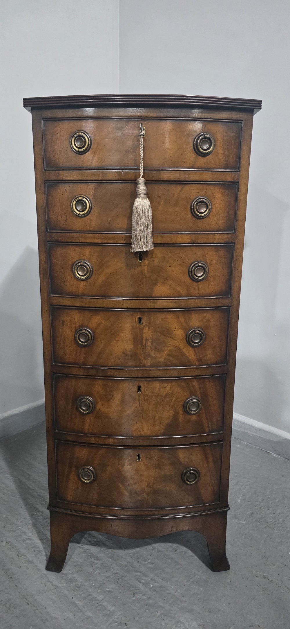 A tall Regency mahogany bowfront chest of drawers featuring six graduated drawers with ring pull handles and bracket feet. View III