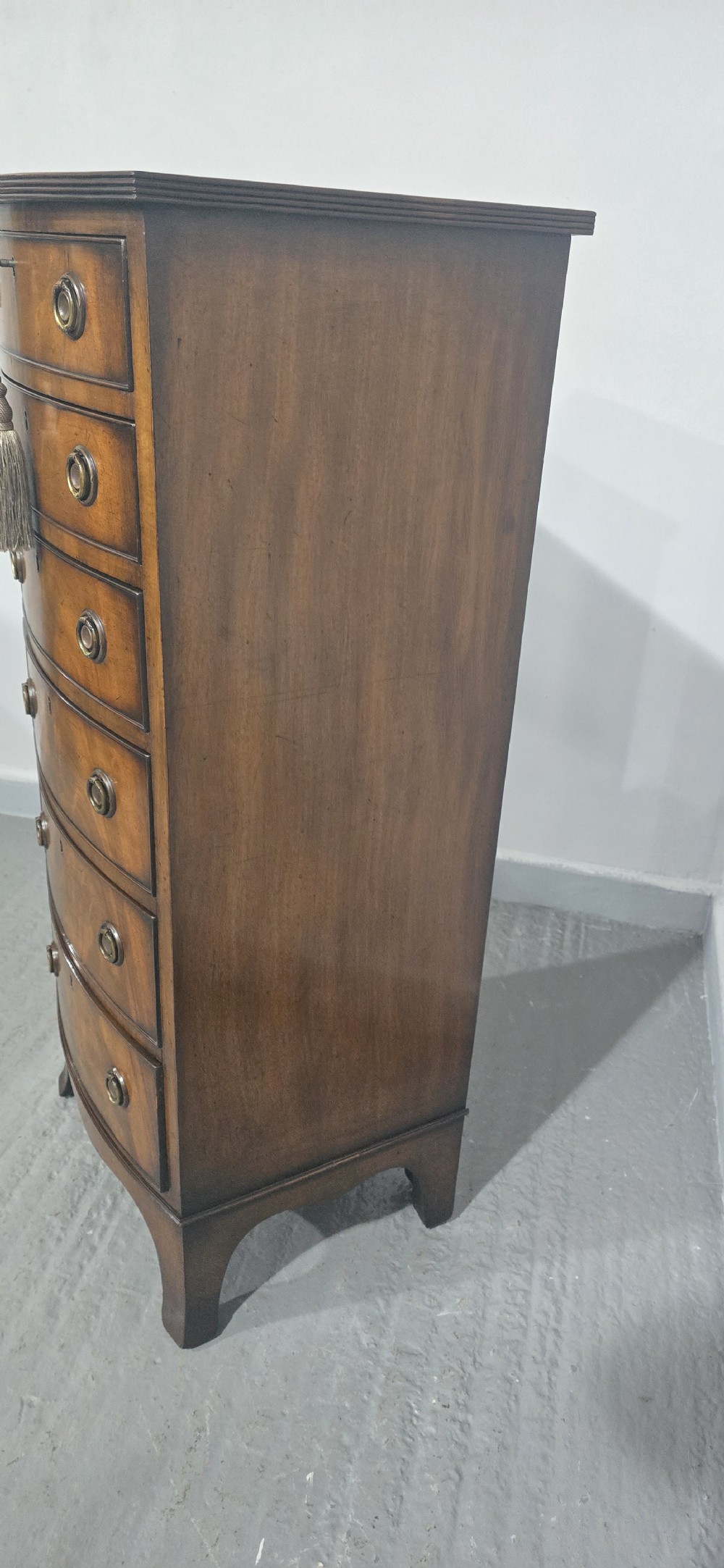 A tall Regency mahogany bowfront chest of drawers featuring six graduated drawers with ring pull handles and bracket feet. View VIII