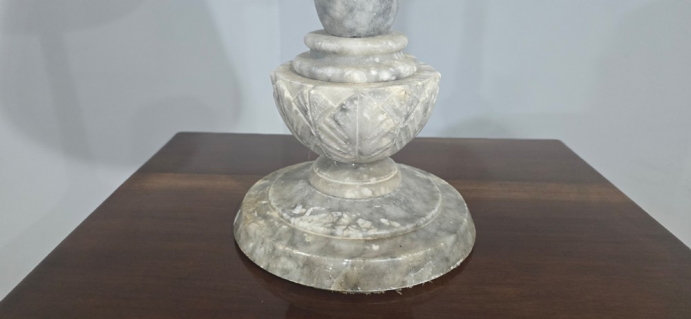 A tall grey marble turned column table lamp base with a tapered beige fabric shade bordered by dark trim. View VI