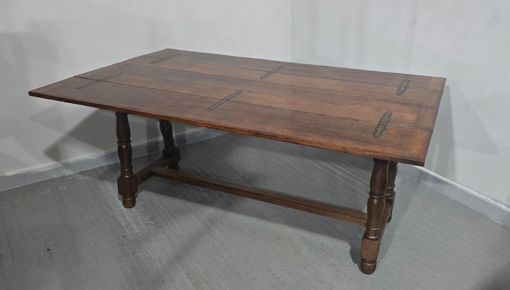 A long rectangular dark oak refectory dining table featuring turned wooden legs, a central stretcher, and a plank top. View V