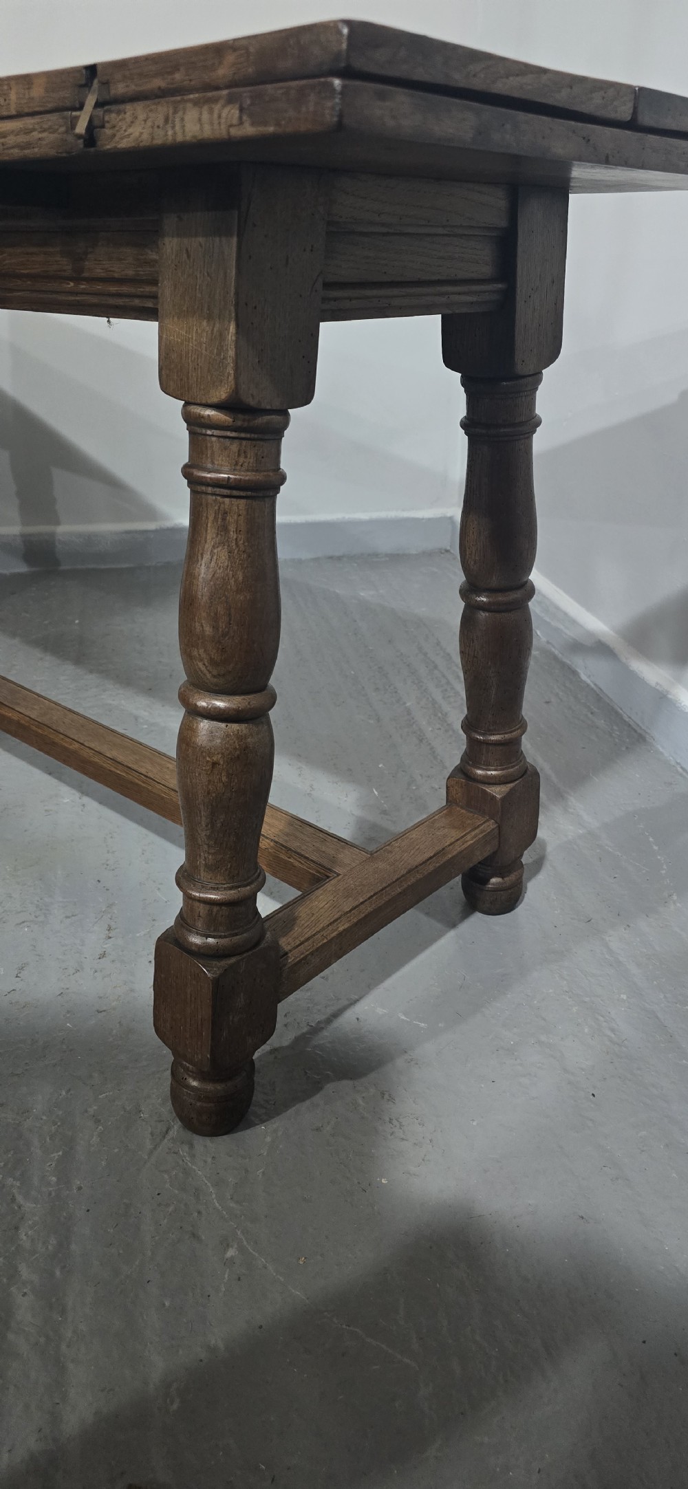 A long rectangular dark oak refectory dining table featuring turned wooden legs, a central stretcher, and a plank top. View XVII