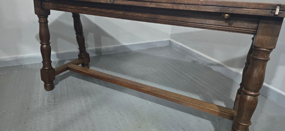 A long rectangular dark oak refectory dining table featuring turned wooden legs, a central stretcher, and a plank top. View XVIII