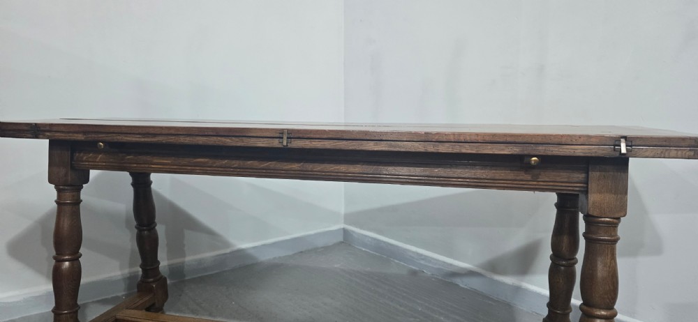 A long rectangular dark oak refectory dining table featuring turned wooden legs, a central stretcher, and a plank top. View XIX