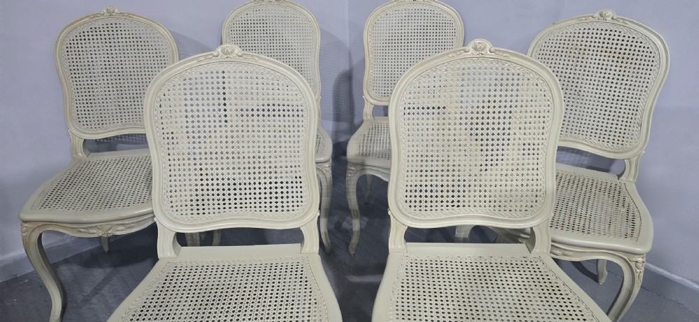 A set of six French-style dining chairs painted in pale grey with woven cane backrests, cane seats, and carved cabriole legs. View IV