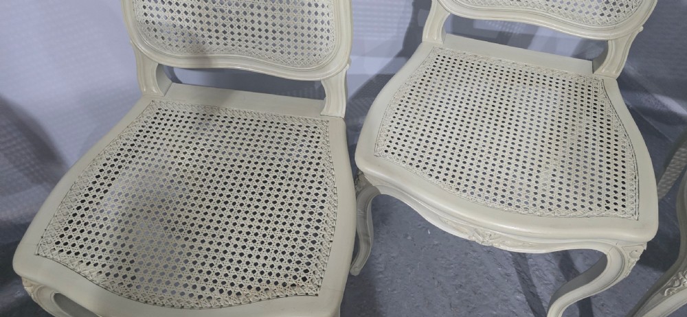 A set of six French-style dining chairs painted in pale grey with woven cane backrests, cane seats, and carved cabriole legs. View V
