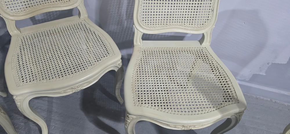 A set of six French-style dining chairs painted in pale grey with woven cane backrests, cane seats, and carved cabriole legs. View VI