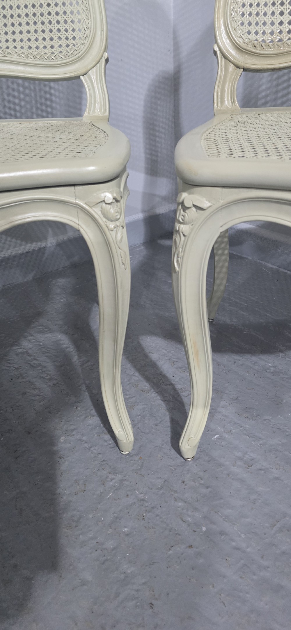 A set of six French-style dining chairs painted in pale grey with woven cane backrests, cane seats, and carved cabriole legs. View X