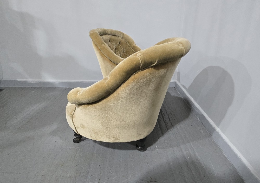 An S-shaped Victorian conversation sofa upholstered in warm gold velvet with deep-buttoned backrests and turned dark timber legs on castors. View IX