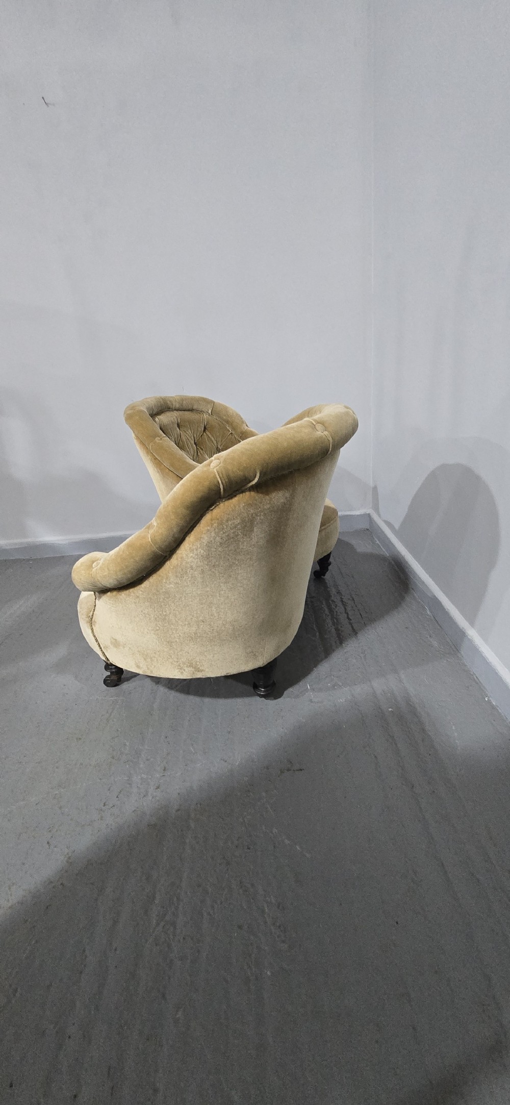 An S-shaped Victorian conversation sofa upholstered in warm gold velvet with deep-buttoned backrests and turned dark timber legs on castors. View X