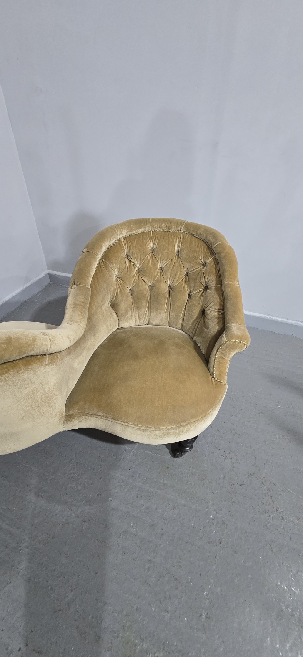 An S-shaped Victorian conversation sofa upholstered in warm gold velvet with deep-buttoned backrests and turned dark timber legs on castors. View XI
