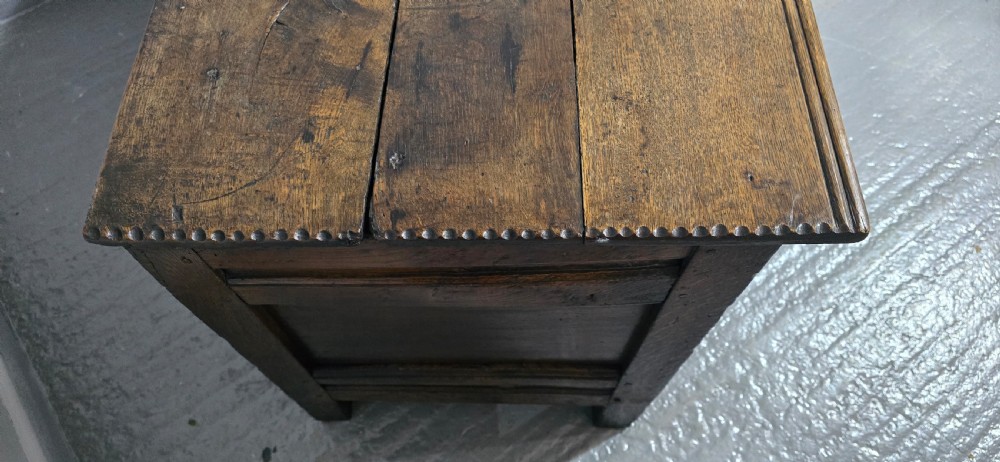 A dark brown Georgian oak coffer featuring a rectangular hinged lid, three recessed front panels, horizontal moulded rails, and an iron lock plate. View V