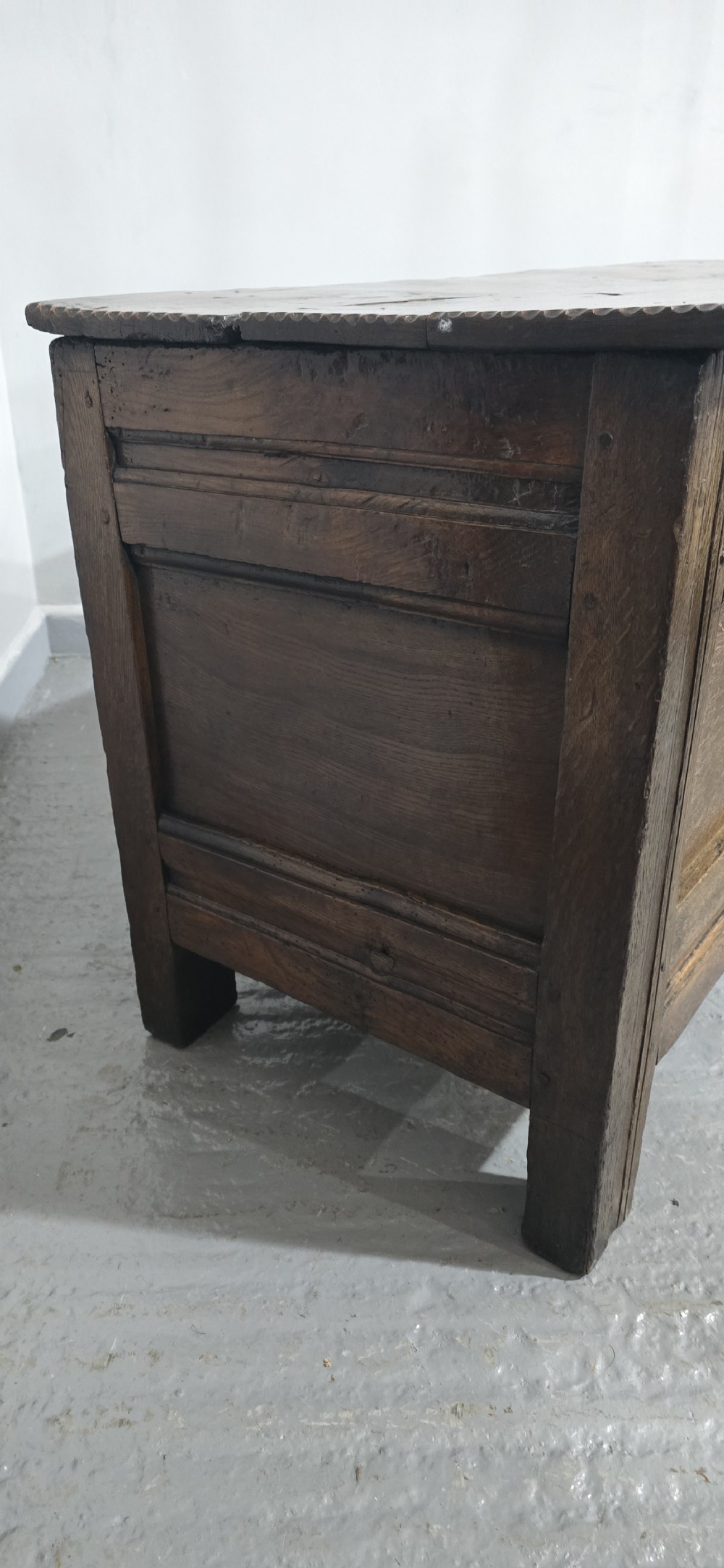 A dark brown Georgian oak coffer featuring a rectangular hinged lid, three recessed front panels, horizontal moulded rails, and an iron lock plate. View VII
