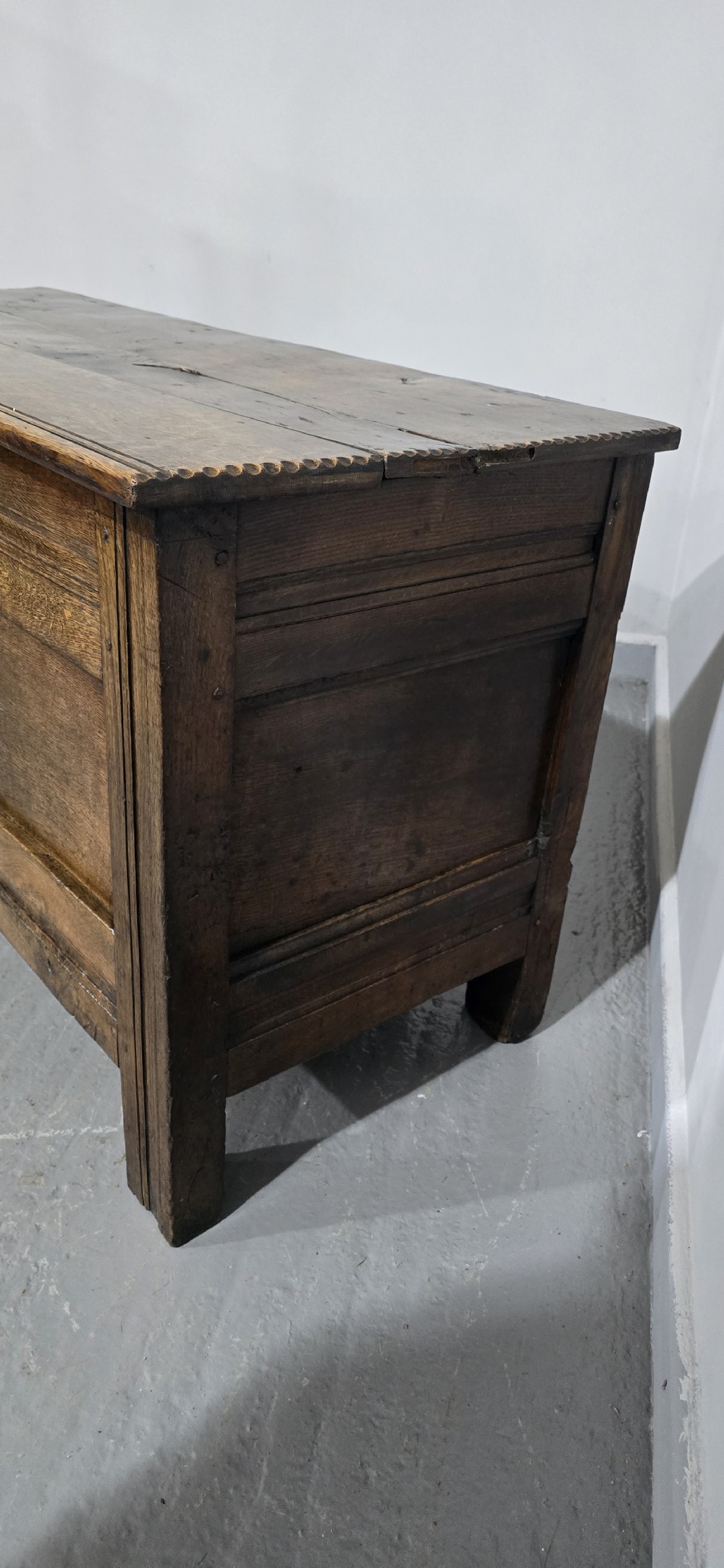 A dark brown Georgian oak coffer featuring a rectangular hinged lid, three recessed front panels, horizontal moulded rails, and an iron lock plate. View VIII