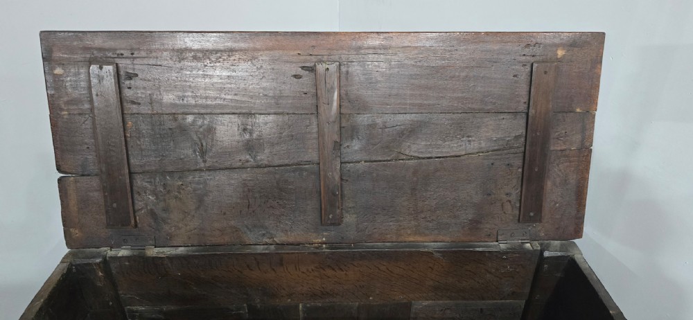 A dark brown Georgian oak coffer featuring a rectangular hinged lid, three recessed front panels, horizontal moulded rails, and an iron lock plate. View IX