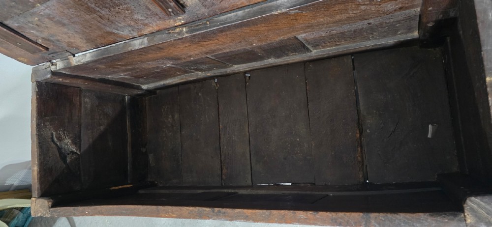 A dark brown Georgian oak coffer featuring a rectangular hinged lid, three recessed front panels, horizontal moulded rails, and an iron lock plate. View X