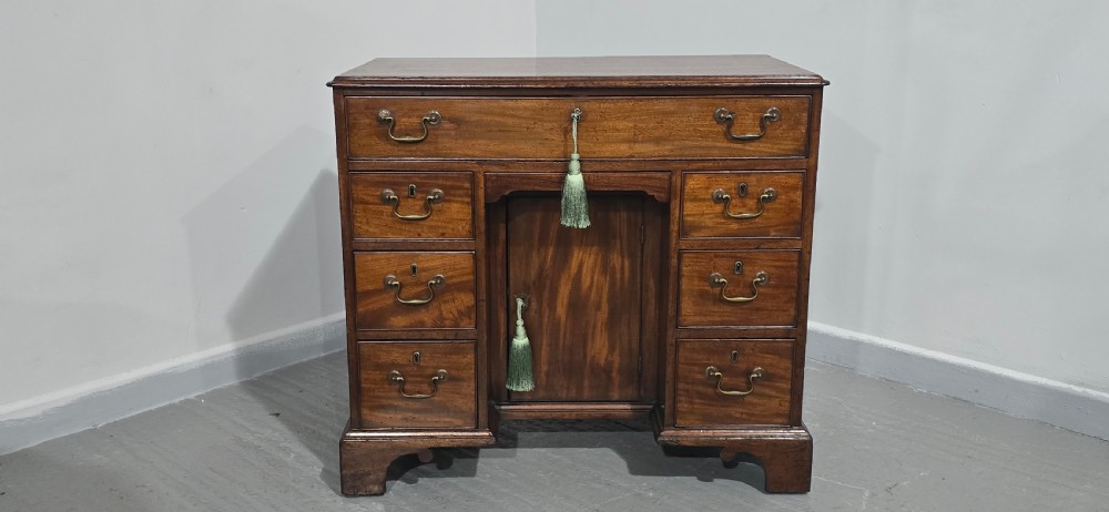 A Georgian mahogany kneehole desk featuring a long top drawer, six side drawers, a central recessed cupboard, brass swan-neck handles, and bracket feet. View III