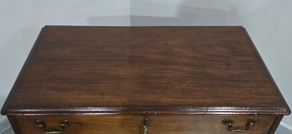 A Georgian mahogany kneehole desk featuring a long top drawer, six side drawers, a central recessed cupboard, brass swan-neck handles, and bracket feet. View VI
