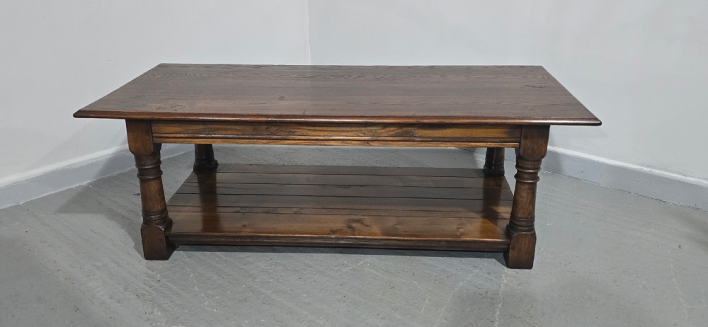 A rectangular dark oak coffee table featuring a plank top, turned legs, and a lower slatted shelf. View II