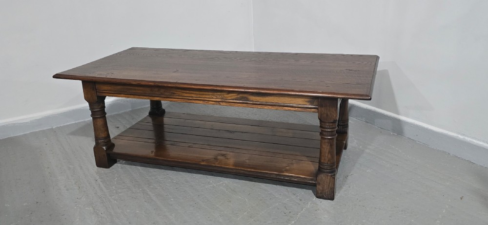 A rectangular dark oak coffee table featuring a plank top, turned legs, and a lower slatted shelf. View IV