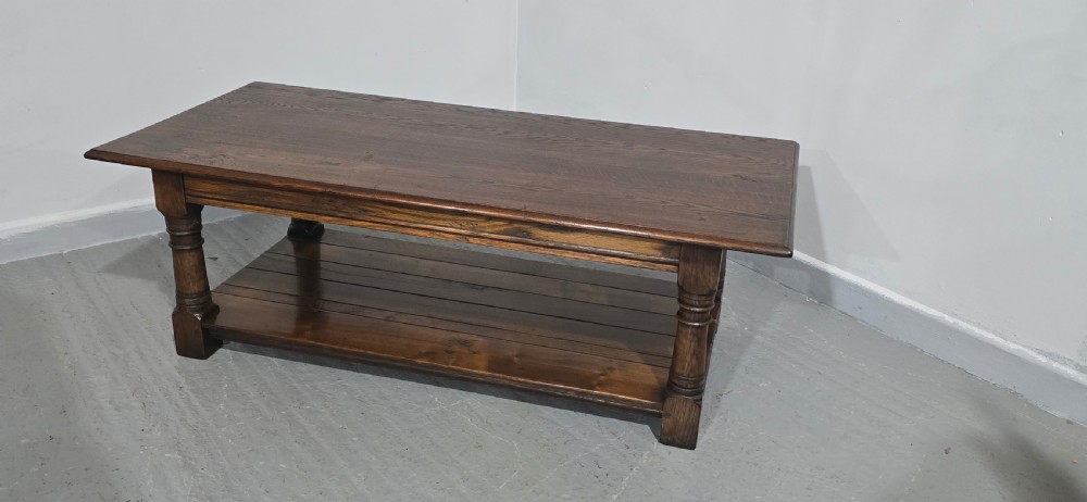 A rectangular dark oak coffee table featuring a plank top, turned legs, and a lower slatted shelf. View V