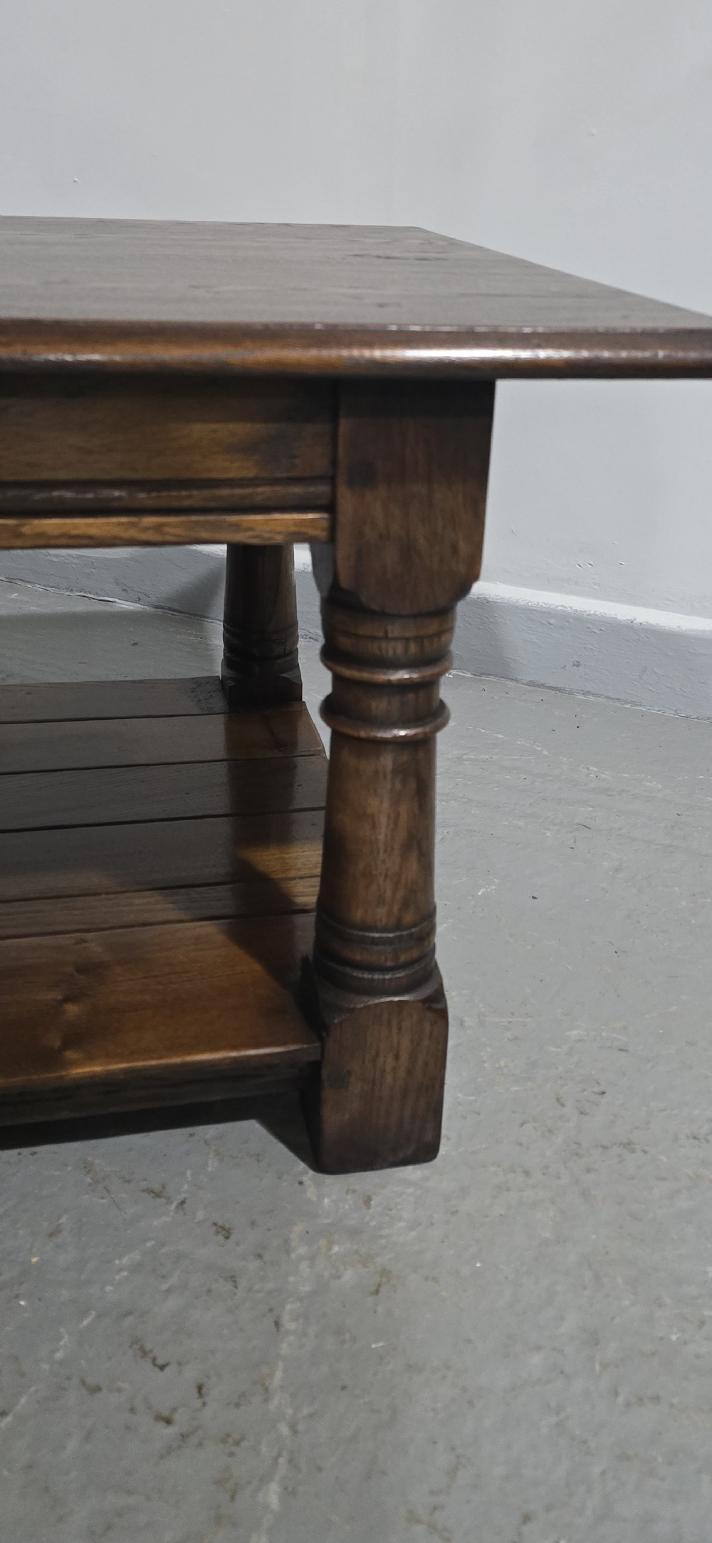 A rectangular dark oak coffee table featuring a plank top, turned legs, and a lower slatted shelf. View VIII