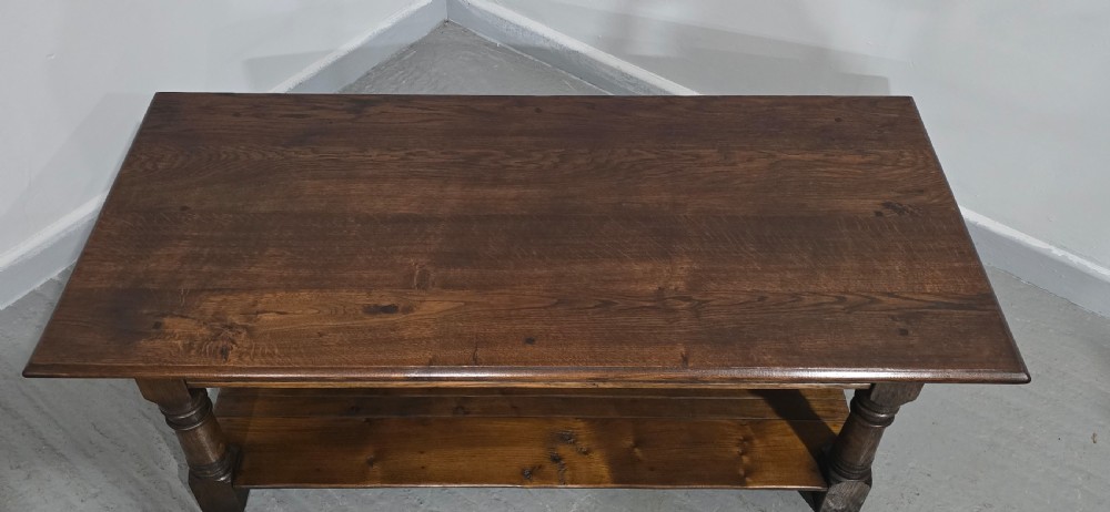 A rectangular dark oak coffee table featuring a plank top, turned legs, and a lower slatted shelf. View IX