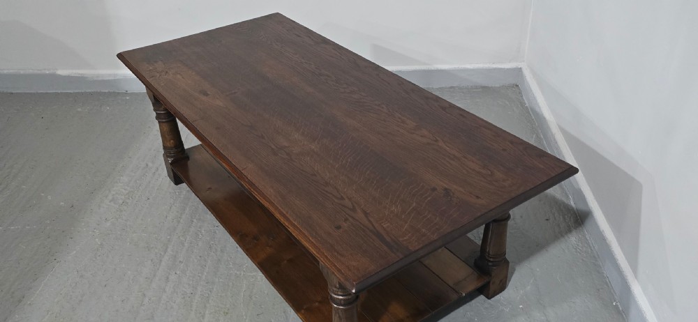 A rectangular dark oak coffee table featuring a plank top, turned legs, and a lower slatted shelf. View XI
