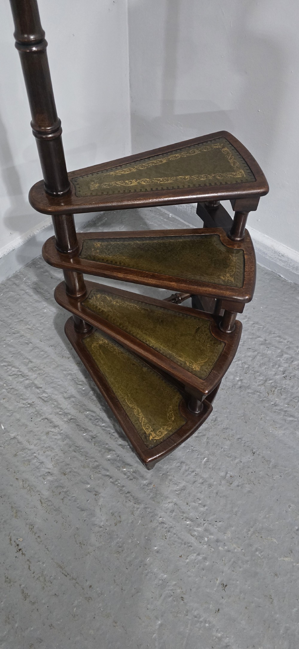 A set of four dark mahogany spiral library steps with green leather inset treads and a tall pole topped with a brass finial. View IV