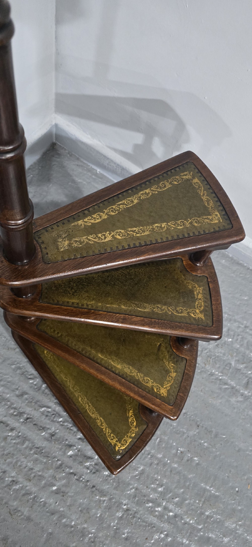 A set of four dark mahogany spiral library steps with green leather inset treads and a tall pole topped with a brass finial. View IX