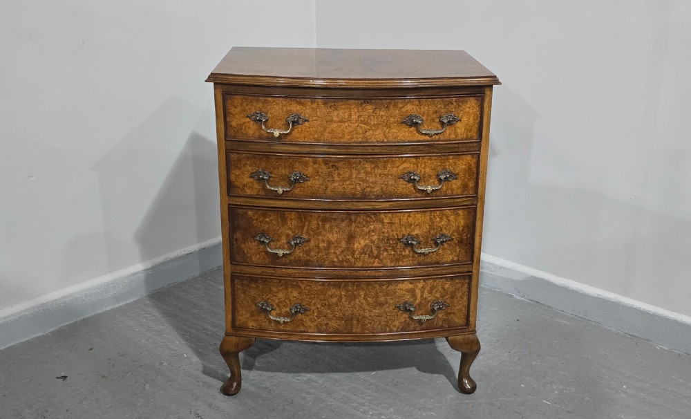 A Queen Anne style burr walnut chest of four graduated drawers featuring a gently curved bow front, brass handles, and cabriole legs. View III