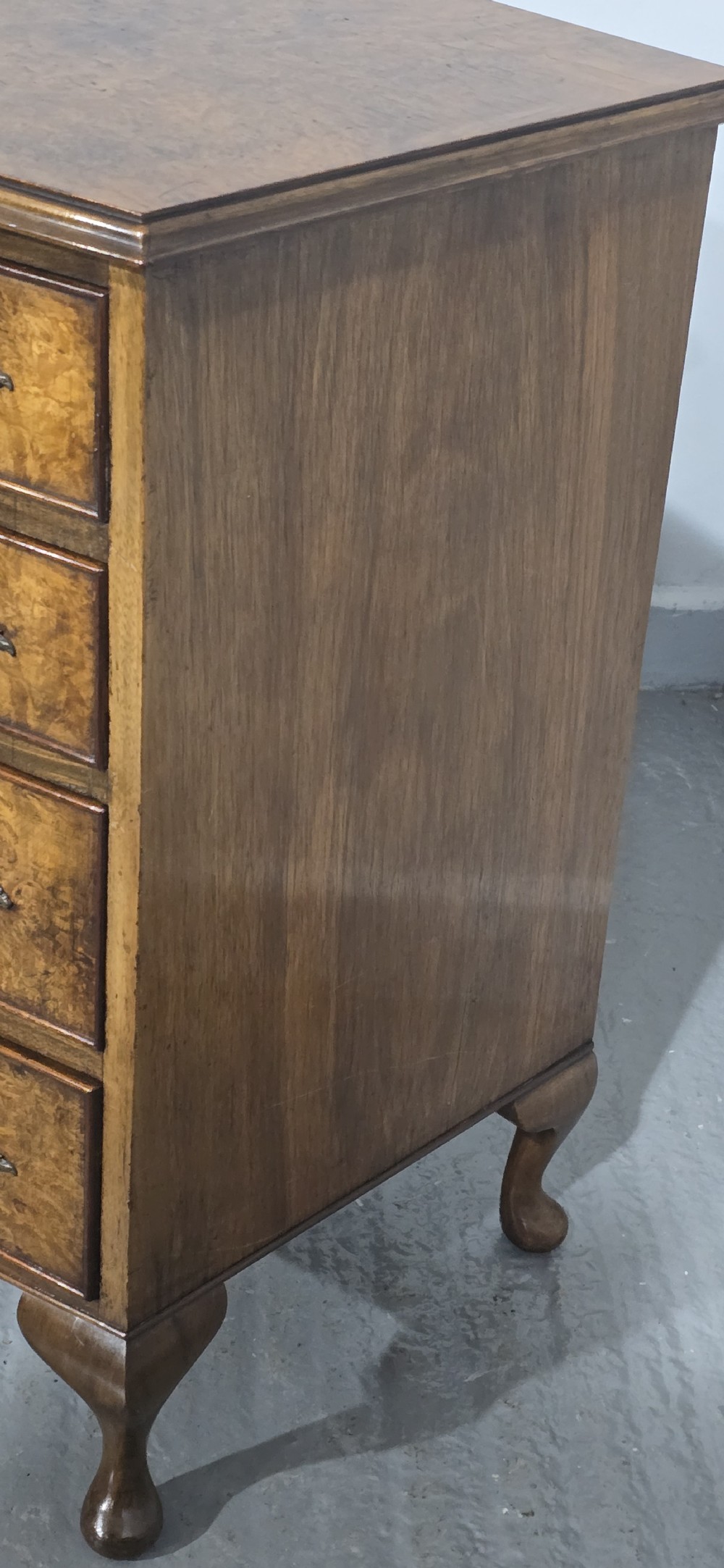 A Queen Anne style burr walnut chest of four graduated drawers featuring a gently curved bow front, brass handles, and cabriole legs. View VII