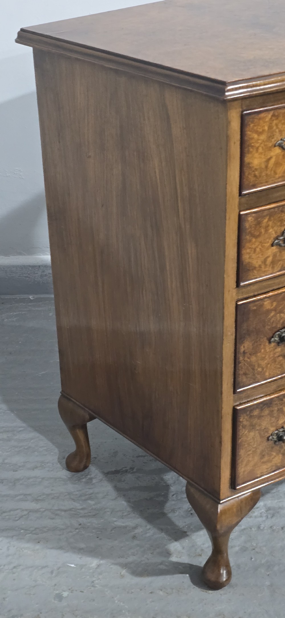 A Queen Anne style burr walnut chest of four graduated drawers featuring a gently curved bow front, brass handles, and cabriole legs. View IX