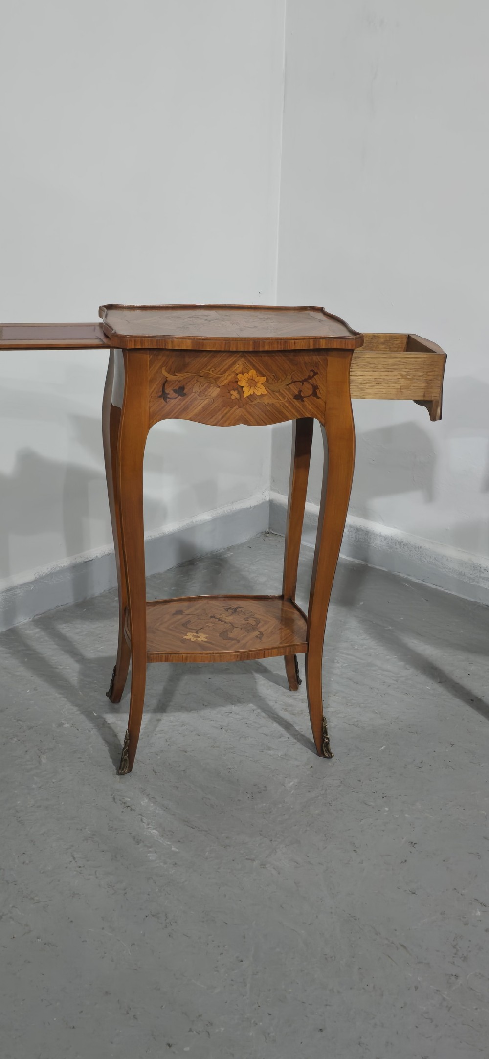 A pair of slender warm brown French marquetry tables featuring floral inlays, cabriole legs, lower shelves, and extended side drawers. View III
