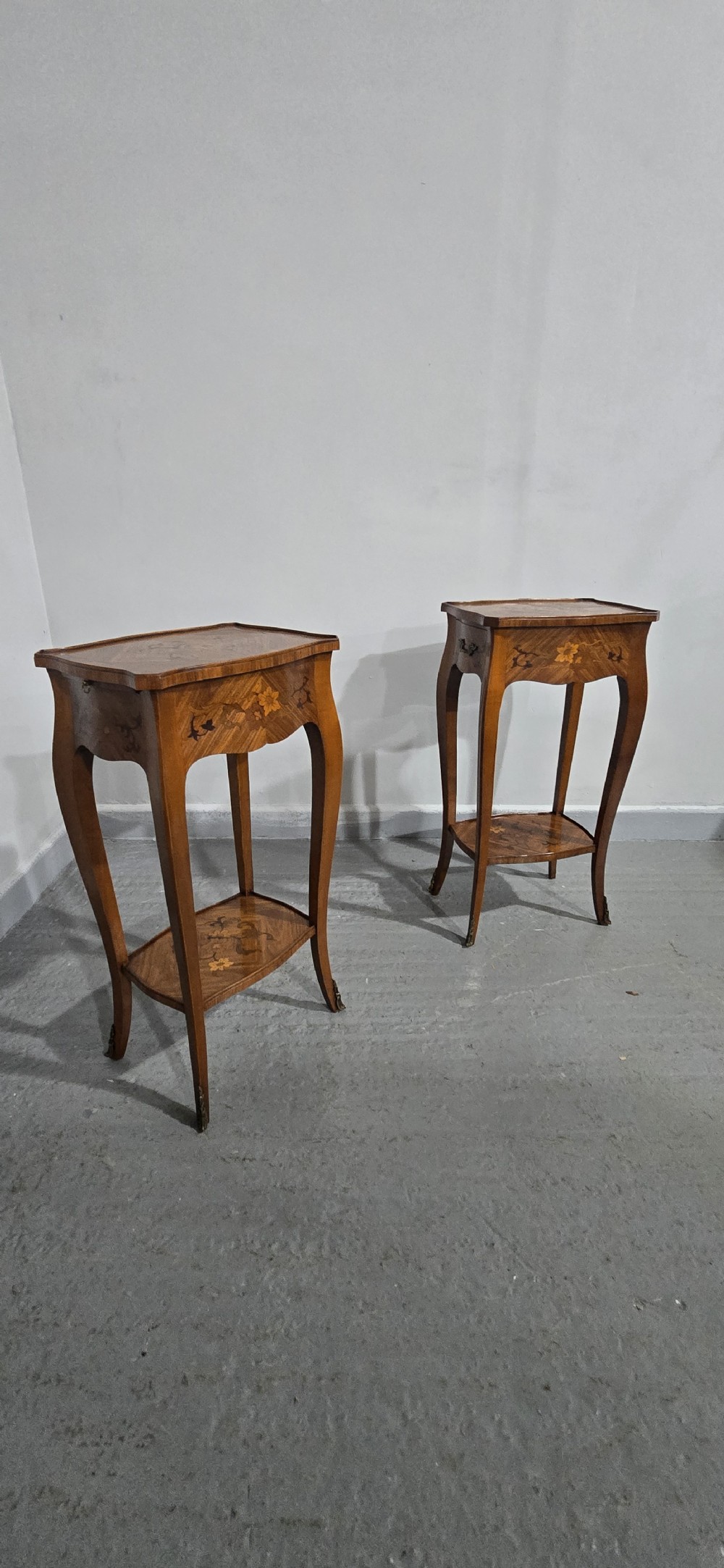 A pair of slender warm brown French marquetry tables featuring floral inlays, cabriole legs, lower shelves, and extended side drawers. View VI