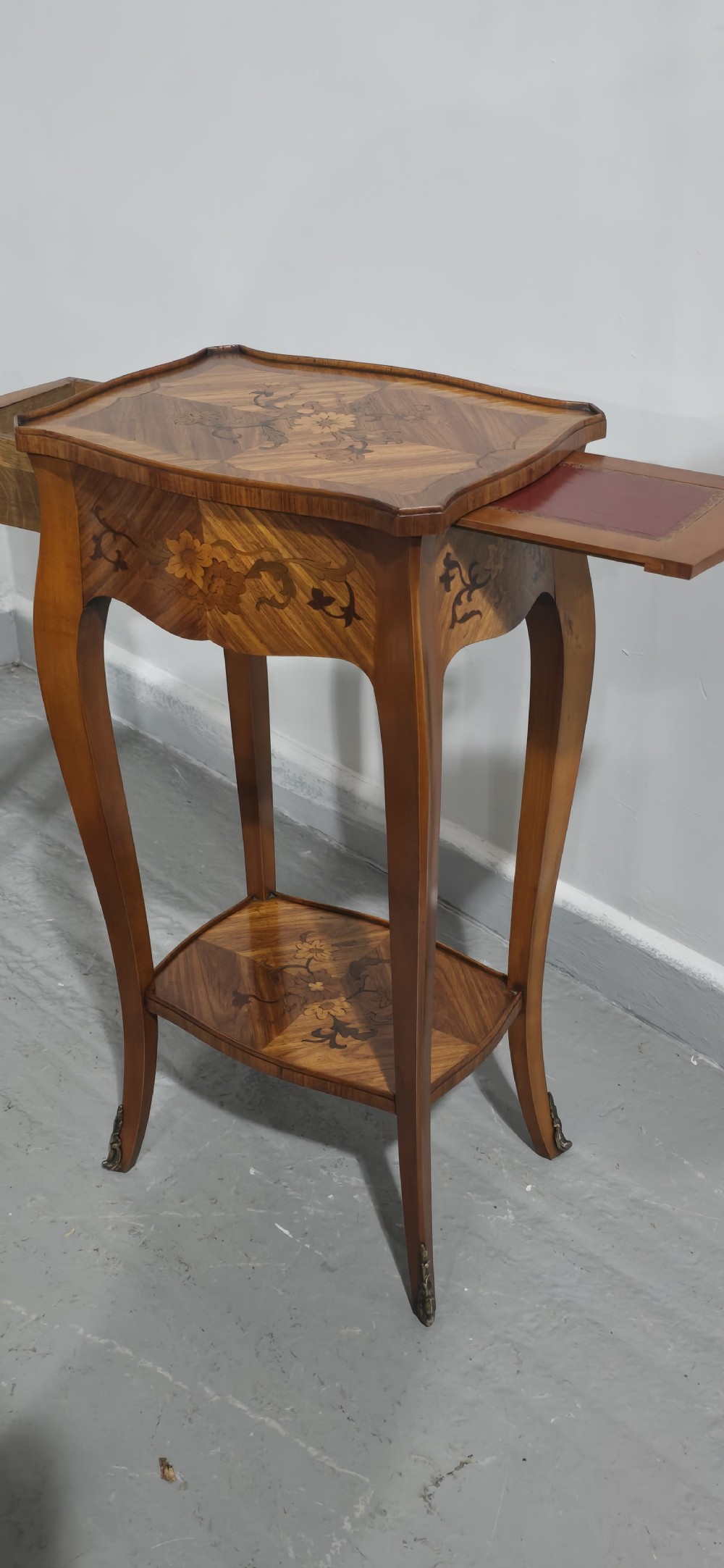 A pair of slender warm brown French marquetry tables featuring floral inlays, cabriole legs, lower shelves, and extended side drawers. View VII