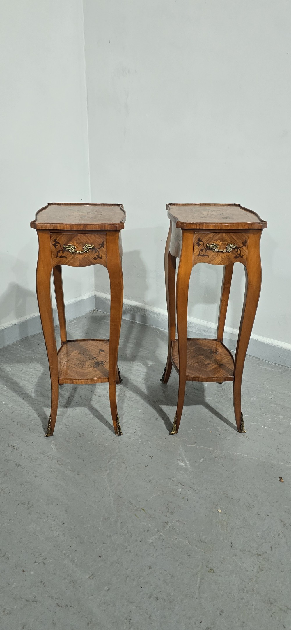 A pair of slender warm brown French marquetry tables featuring floral inlays, cabriole legs, lower shelves, and extended side drawers. View X