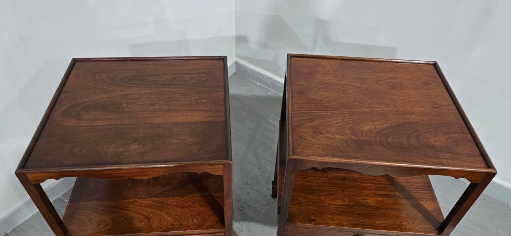 A pair of Georgian mahogany lamp tables featuring tray top rims, middle open shelves, single drawers with brass knobs, and shaped aprons. View IV
