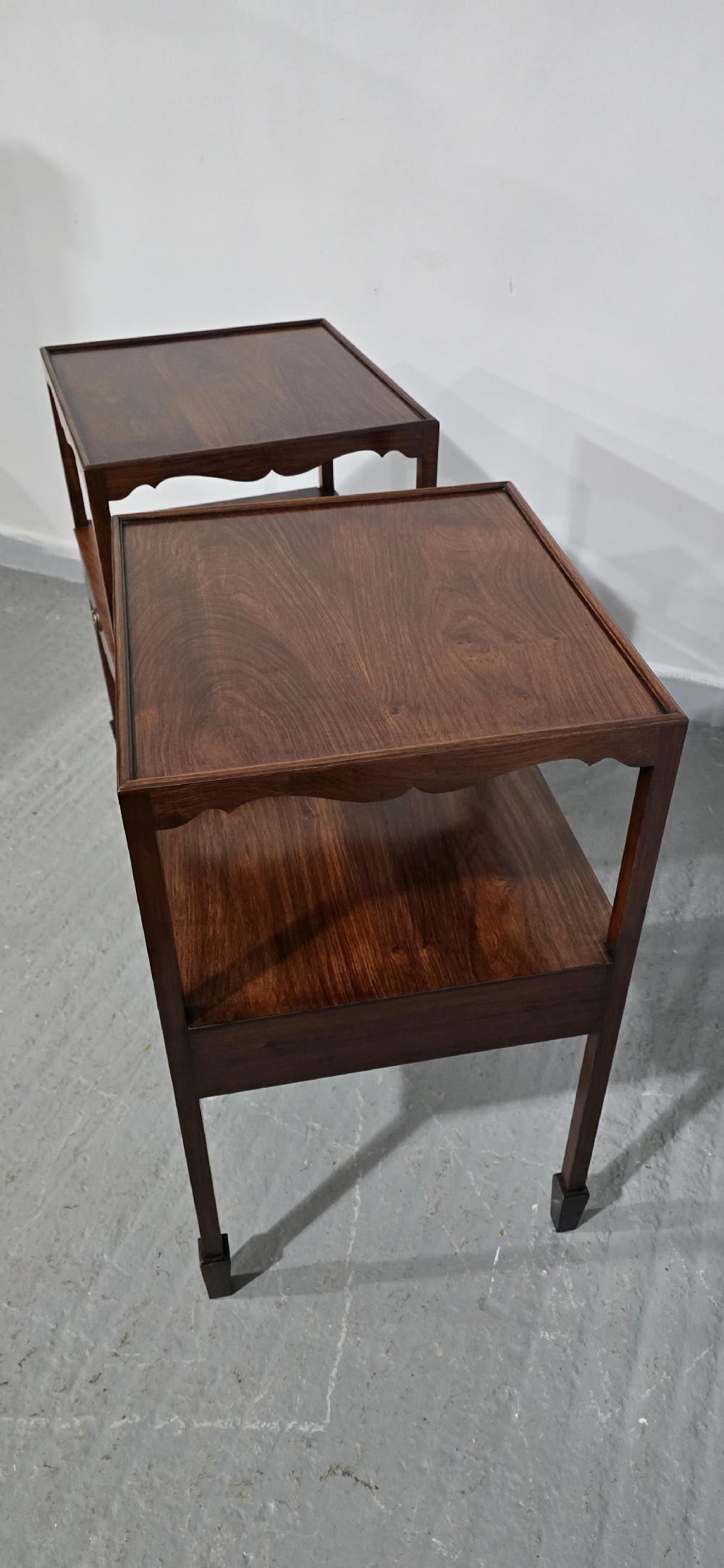 A pair of Georgian mahogany lamp tables featuring tray top rims, middle open shelves, single drawers with brass knobs, and shaped aprons. View V