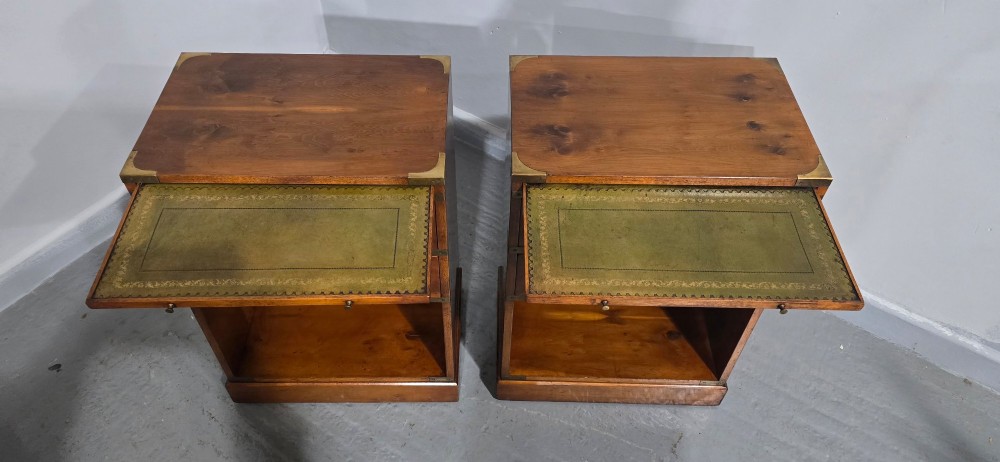 A pair of warm brown yew wood campaign style bedside tables featuring brass corner mounts, flush brass pull handles, drawers, and lower open shelves. View V